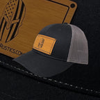 Breacher Rustics black cotton/nylon trucker hat with American flag Spartan helmet patch and grey mesh back. Adjustable snapback.
