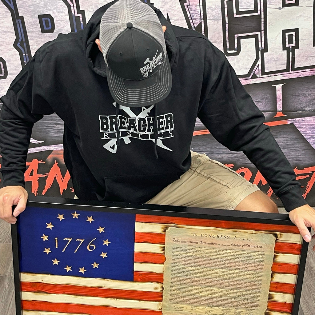 Breacher Rustics black cotton blend pullover hoodie with logo, muff pocket, and ribbed details. Worn by a man with a baseball cap. breacher rustics hoodie patriotic apparel military first responder hoodie soft athletic fit usa made style