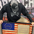 Breacher Rustics black cotton blend pullover hoodie with logo, muff pocket, and ribbed details. Worn by a man with a baseball cap. breacher rustics hoodie patriotic apparel military first responder hoodie soft athletic fit usa made style