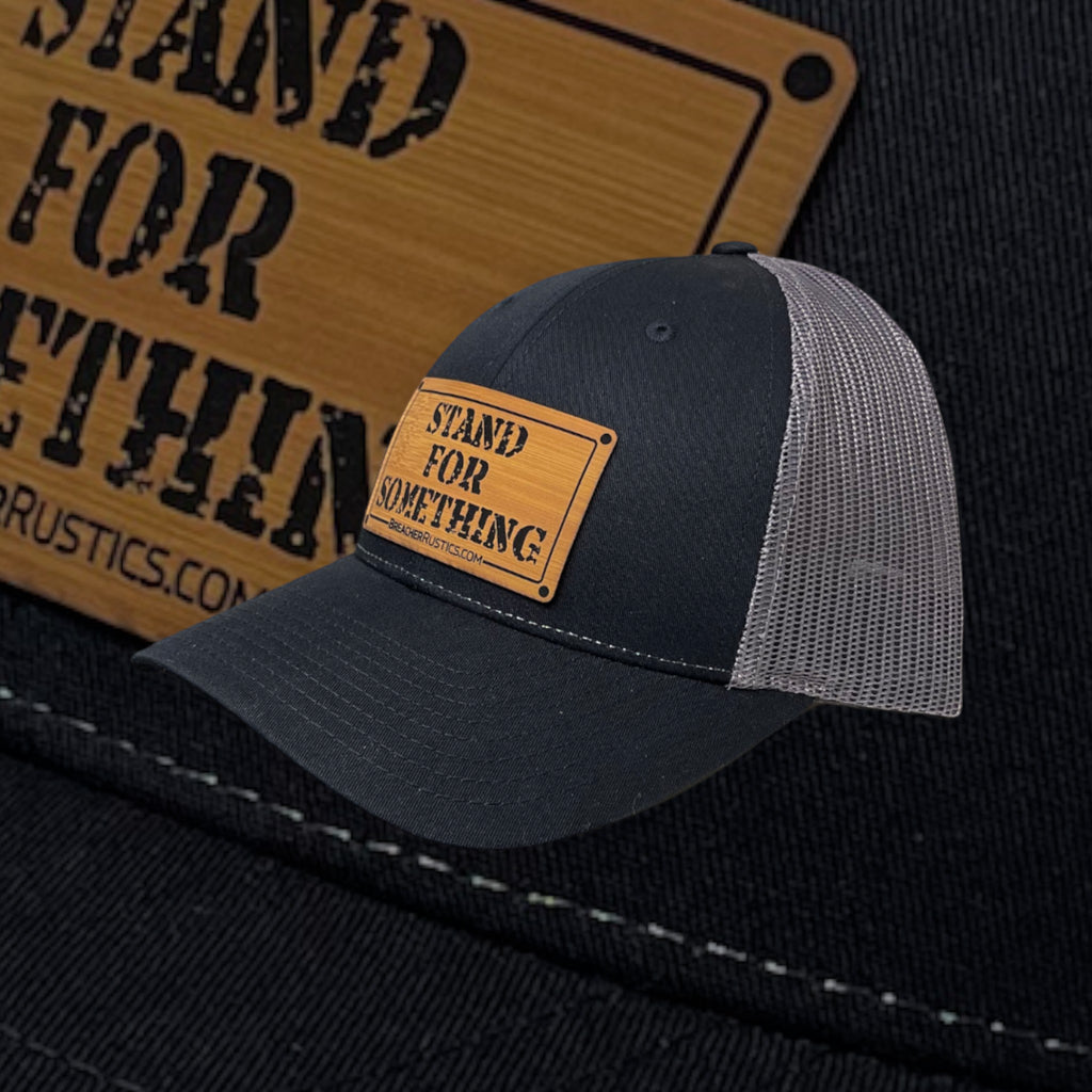 Breacher Rustics black cotton trucker hat with grey mesh back and bamboo leather patch with "Stand For Something" logo.