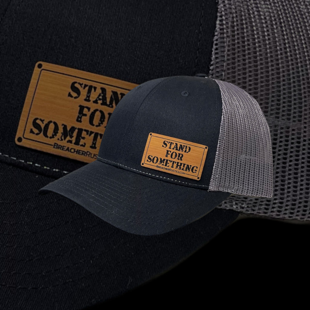 Breacher Rustics black cotton trucker hat with grey mesh back and bamboo leather patch that says Stand For Something.