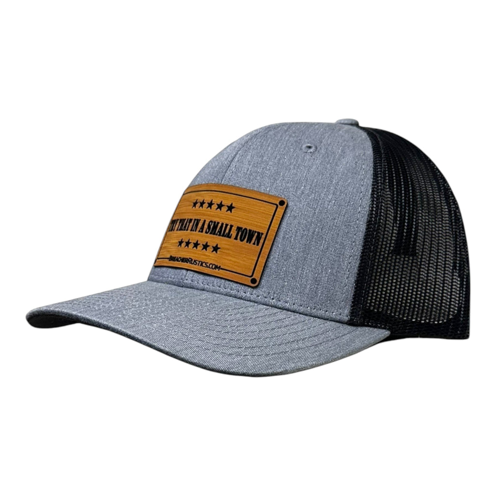 Breacher Rustics trucker hat with a bamboo leather patch featuring "Try That In A Small Town" text and stars. Grey front panels and black mesh back. Jason Aldean.