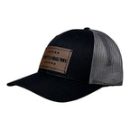 Breacher Rustics black trucker hat with grey mesh back and a brown leather patch that says "Try That In A Small Town" Jason Aldean.