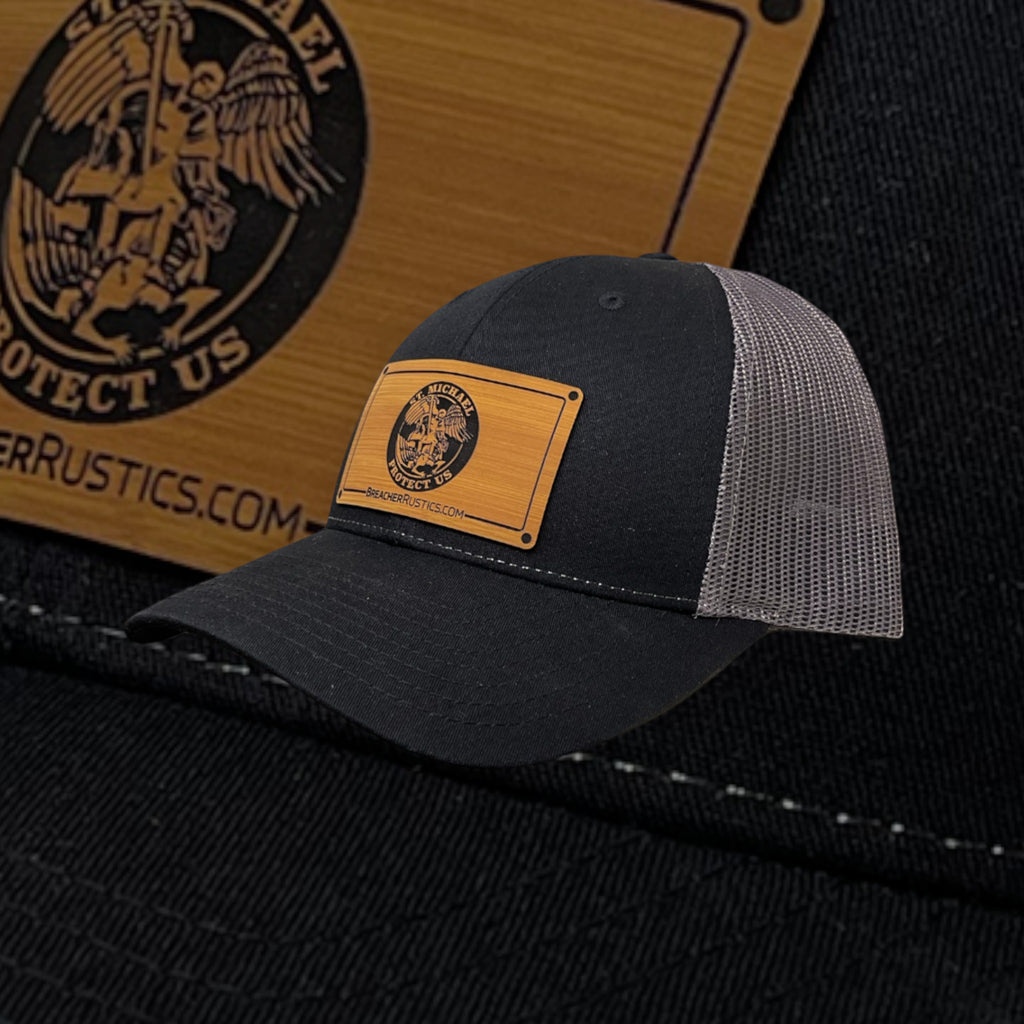 Breacher Rustics black trucker hat with St. Michael patch and grey mesh back. Cotton/nylon blend.