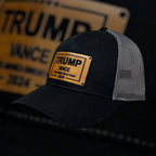 Breacher Rustics Trump Vance 2024 black trucker hat with bamboo leather patch and grey mesh back. Adjustable snapback.