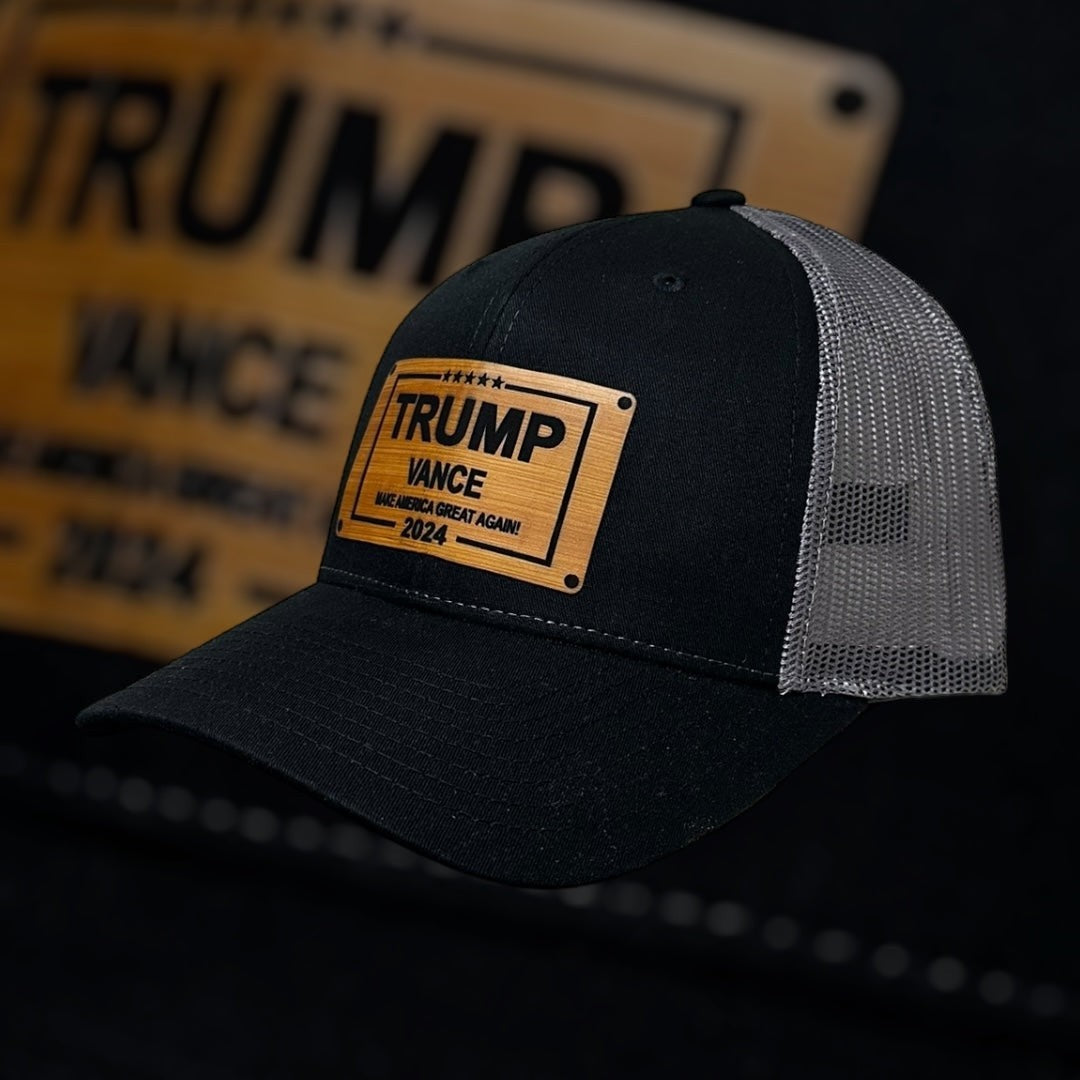 Breacher Rustics Trump Vance 2024 black trucker hat with bamboo leather patch and grey mesh back. Adjustable snapback.