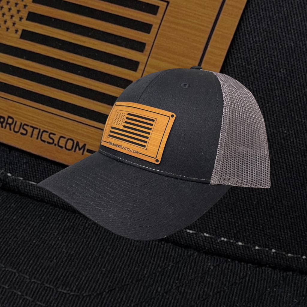 Breacher Rustics charcoal grey trucker hat with a bamboo leather patch featuring the USA flag and "BREACHER RUSTICS.COM".