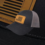 Breacher Rustics charcoal grey trucker hat with a bamboo leather patch featuring the USA flag and "BREACHER RUSTICS.COM".