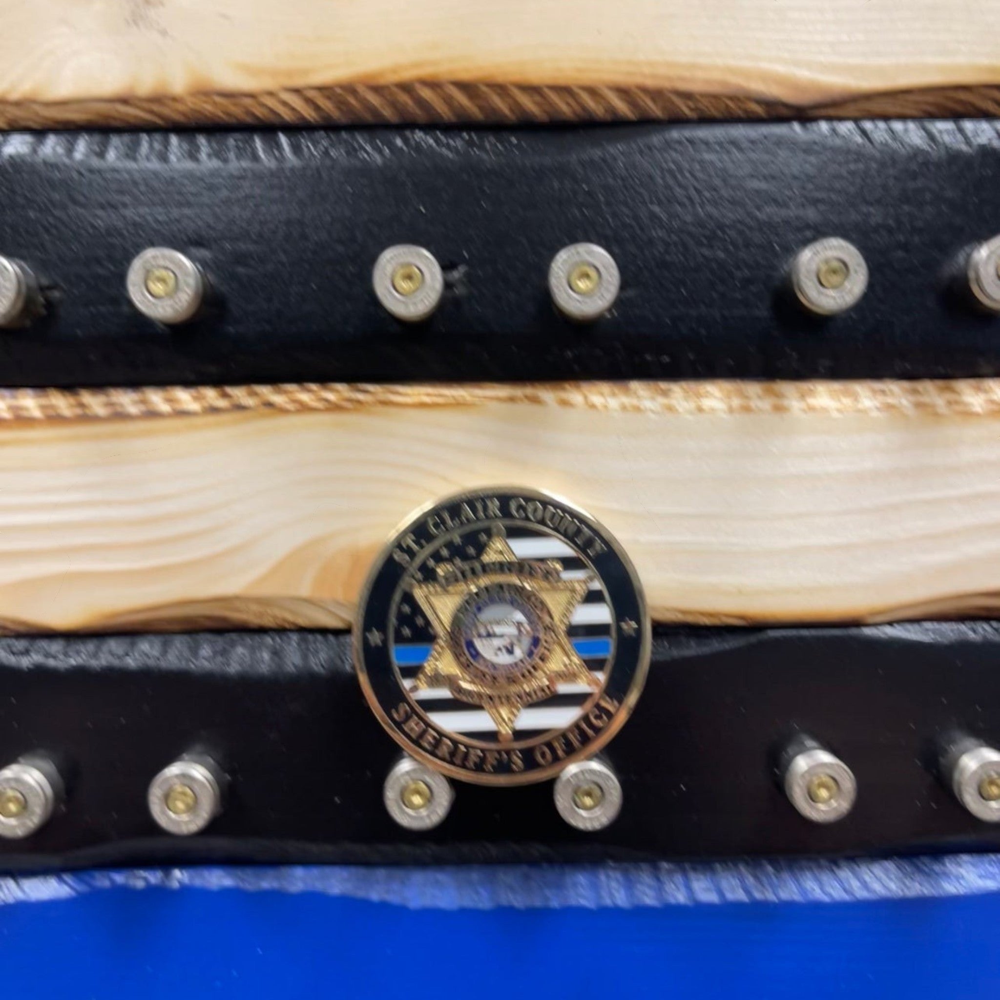 Breacher Rustics wooden flag with black stripes, 9mm casings, and a St. Clair County Sheriff's Office challenge coin. police challenge coin display flag thin blue line wooden rack for coins military and law enforcement gift